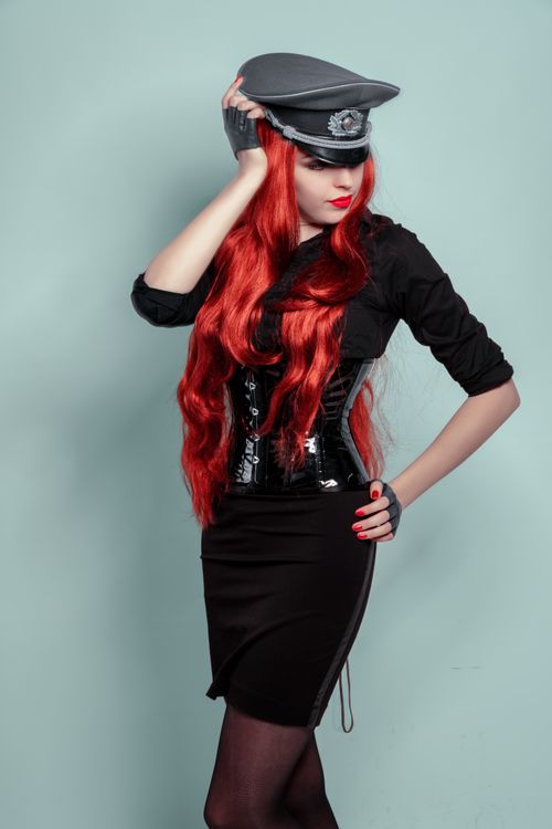 Free Portrait of a stylish redhead woman in a black outfit with military cap posing confidently. Stock Photo