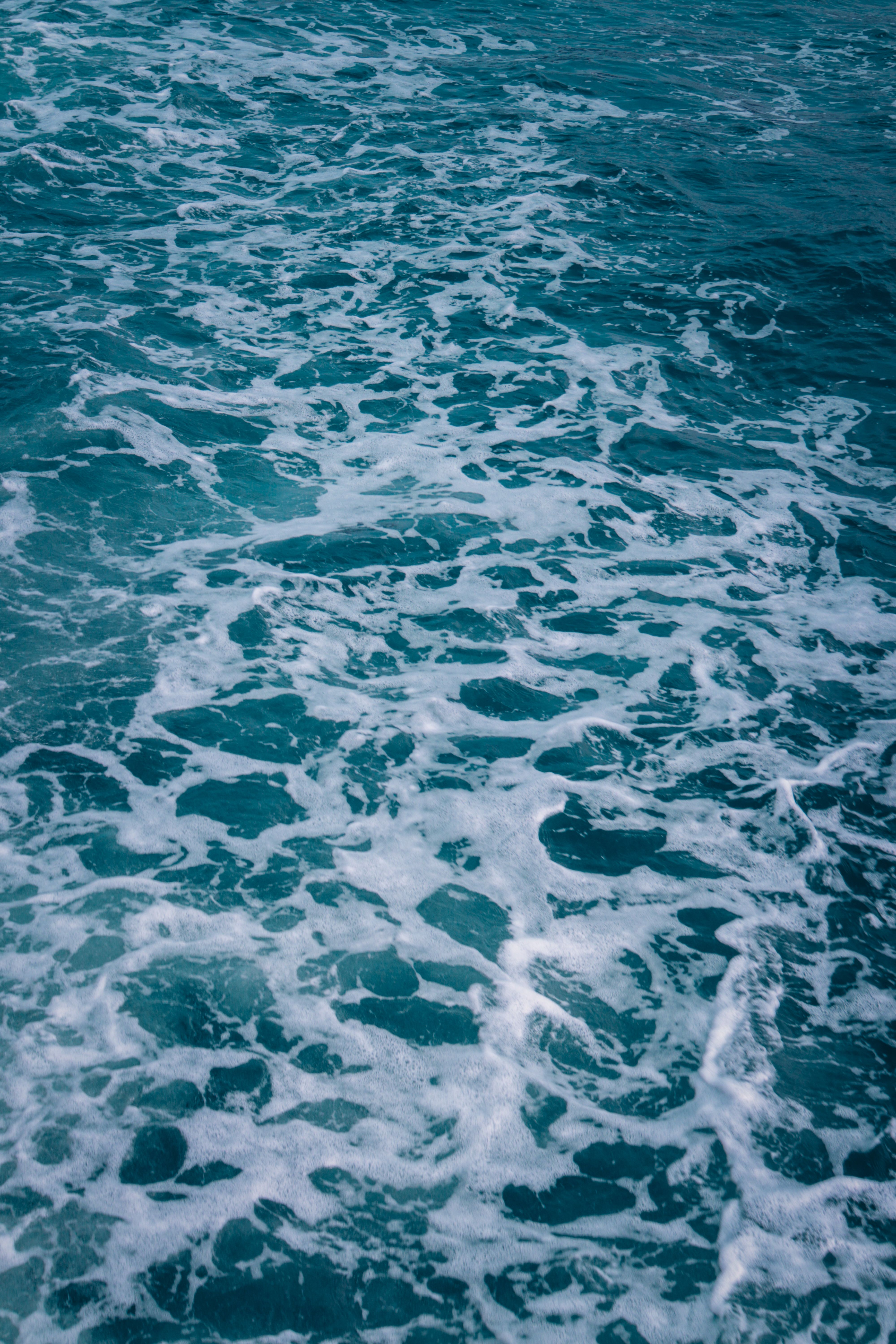 Captivating view of ocean waves creating intricate patterns of white foam on the surface.