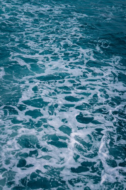 Free Captivating view of ocean waves creating intricate patterns of white foam on the surface. Stock Photo