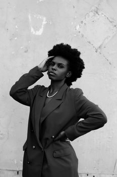 Stylish monochrome portrait of confident woman in blazer posing against textured wall.