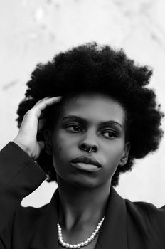 Striking monochrome portrait of a woman with afro hairstyle and nose piercing, exuding grace.
