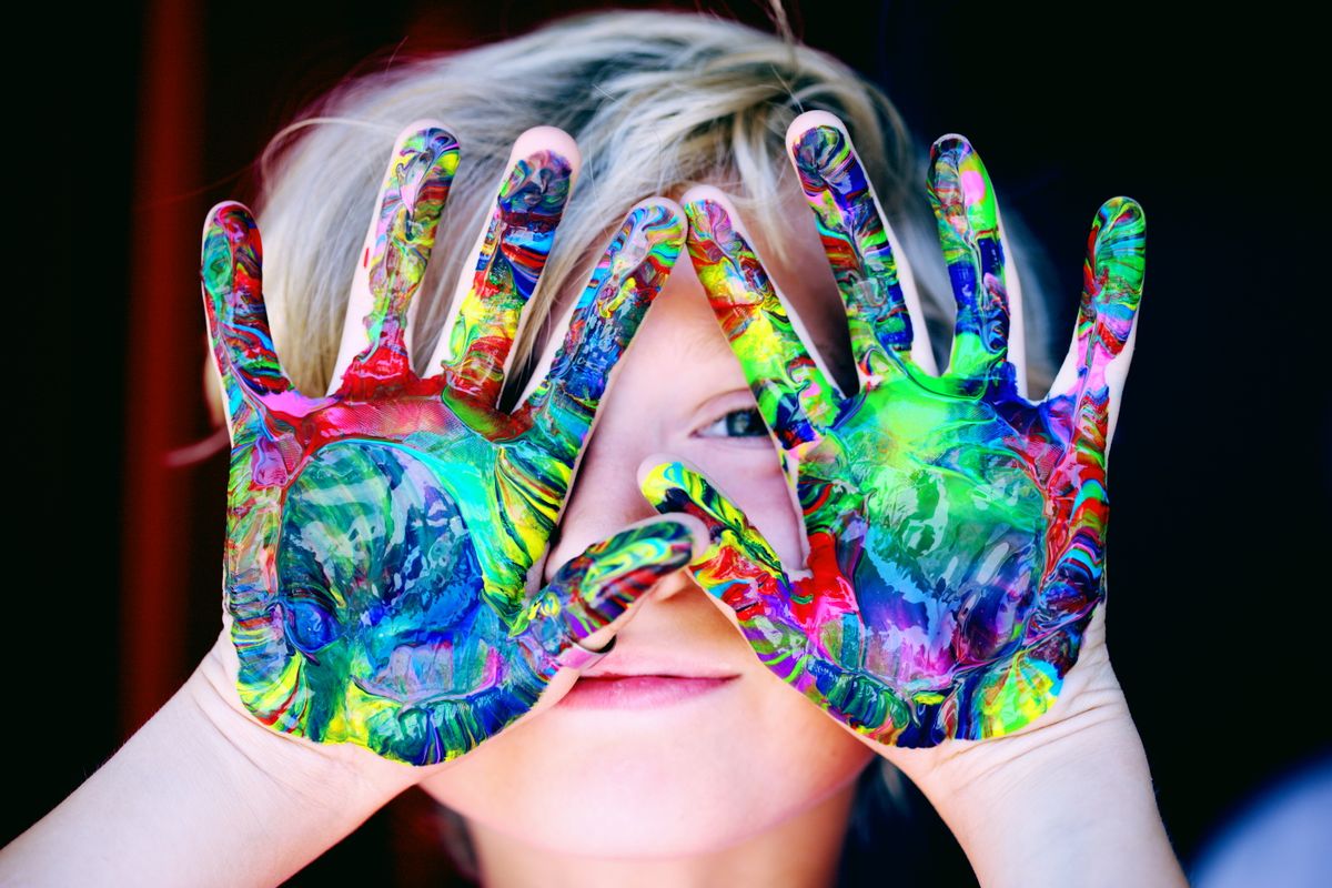 A child's hands covered in bright, colorful finger paint