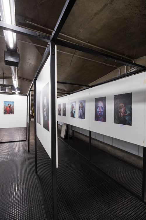 Free A modern urban art exhibition featuring diverse portrait photography displayed in a subway-like gallery space. Stock Photo