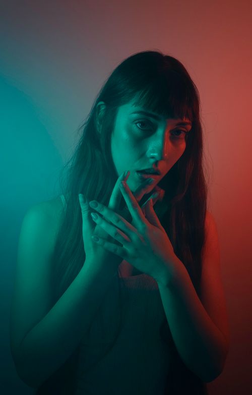 Free A mysterious and artistic portrait of a woman illuminated by vibrant colored lighting. Stock Photo
