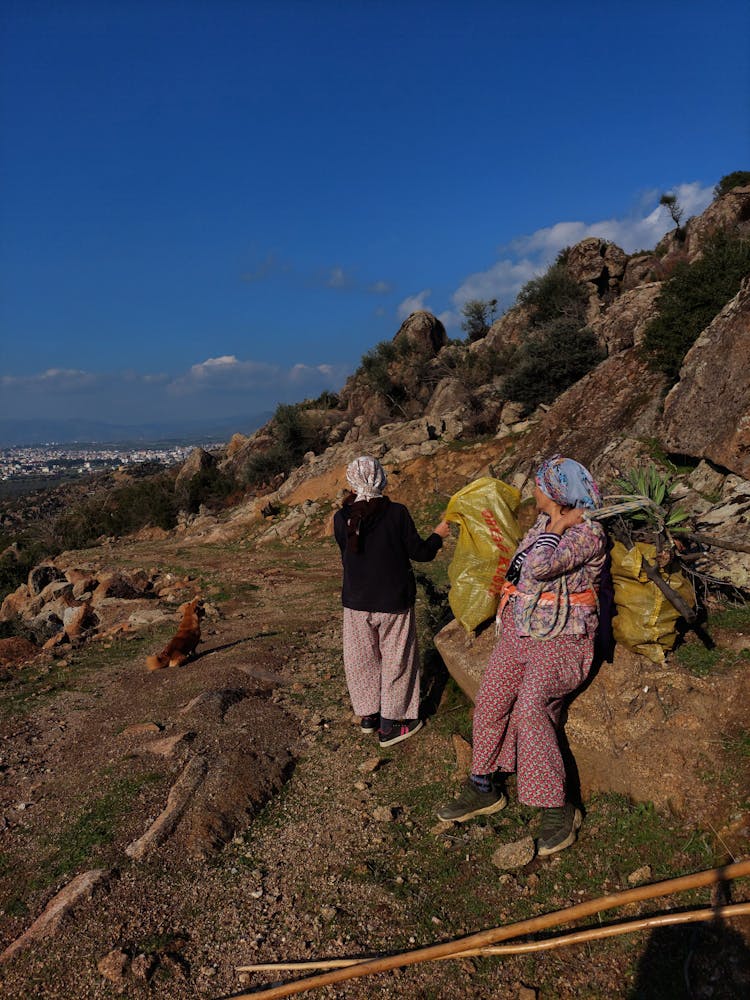 Women Walking Down A Path Carrying Bags