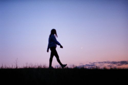 Free A person strolling against a serene twilight background with a crescent moon. Stock Photo