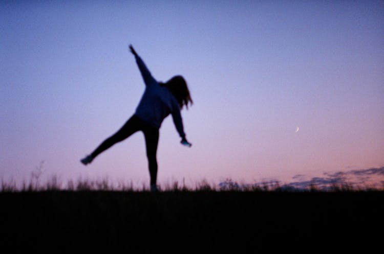 Silhouette Of A Person Jumping On A Grassy Field