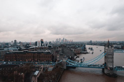 Free A stunning aerial view of Tower Bridge showcasing London's iconic skyline under a cloudy sky. Stock Photo