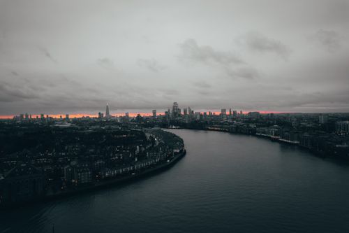 Free A stunning aerial view of London's cityscape and Thames River under a moody twilight sky. Stock Photo