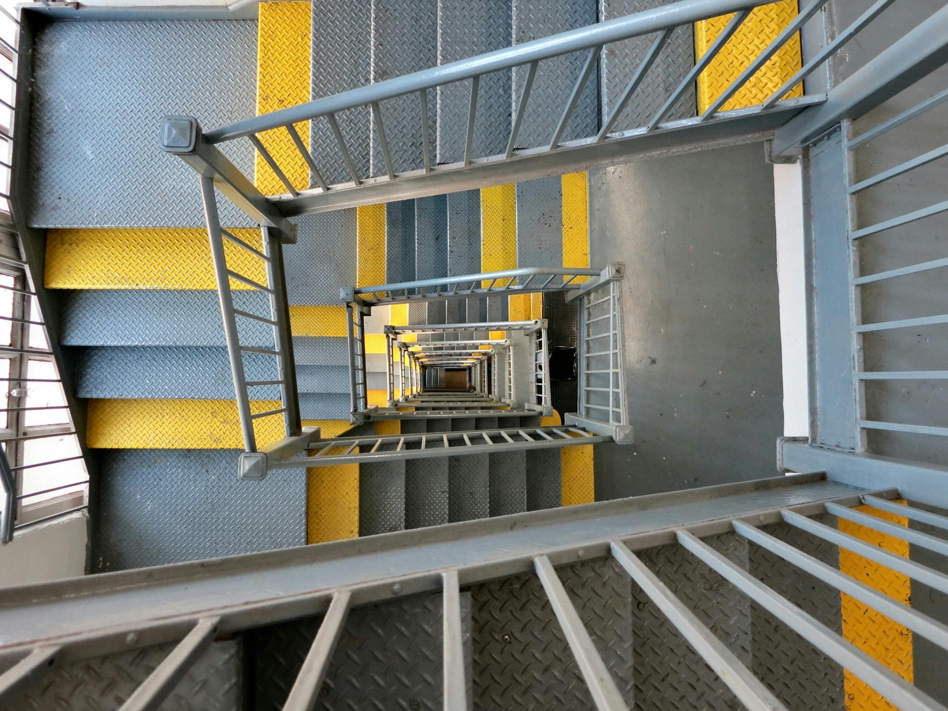 Top view of a metal staircase with yellow markings in New York City, showcasing geometric patterns.