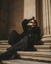 Female Fashion Model in Black Warm Clothes Laying on Stone Stairs