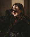 Brunette Woman in Black Furry Coat Looking Over Sunglasses