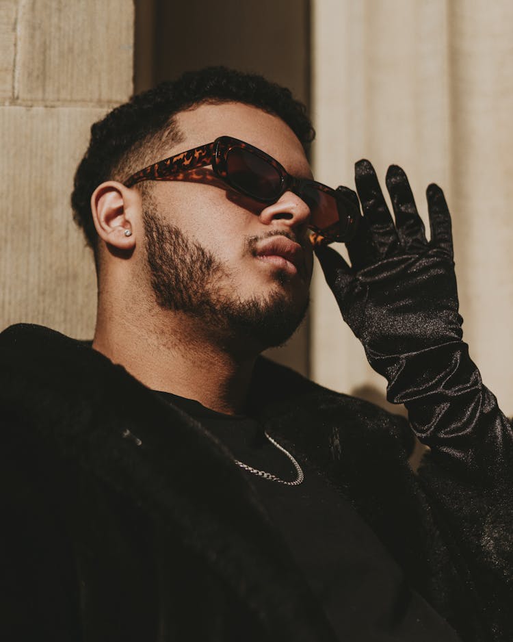 Male Model Wearing Black Outfit And Female Glove Looking Through Sunglasses