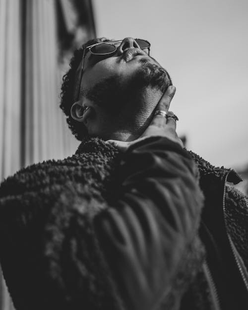 Grayscale Photo of a Man Touching His Neck