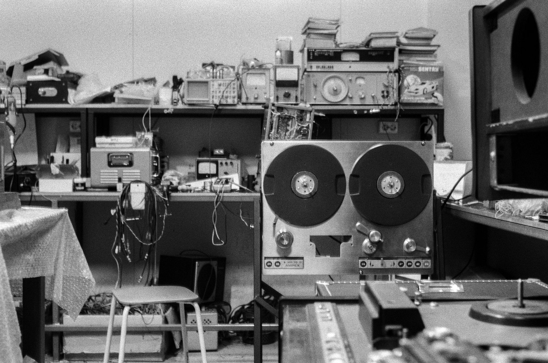 Black and white photo of a nostalgic audio repair shop featuring a reel-to-reel tape machine and various equipment.