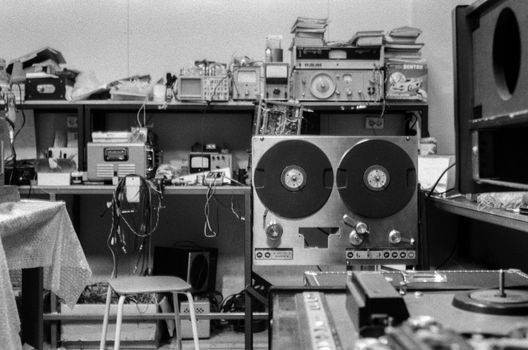 Black and white photo of a nostalgic audio repair shop featuring a reel-to-reel tape machine and various equipment.