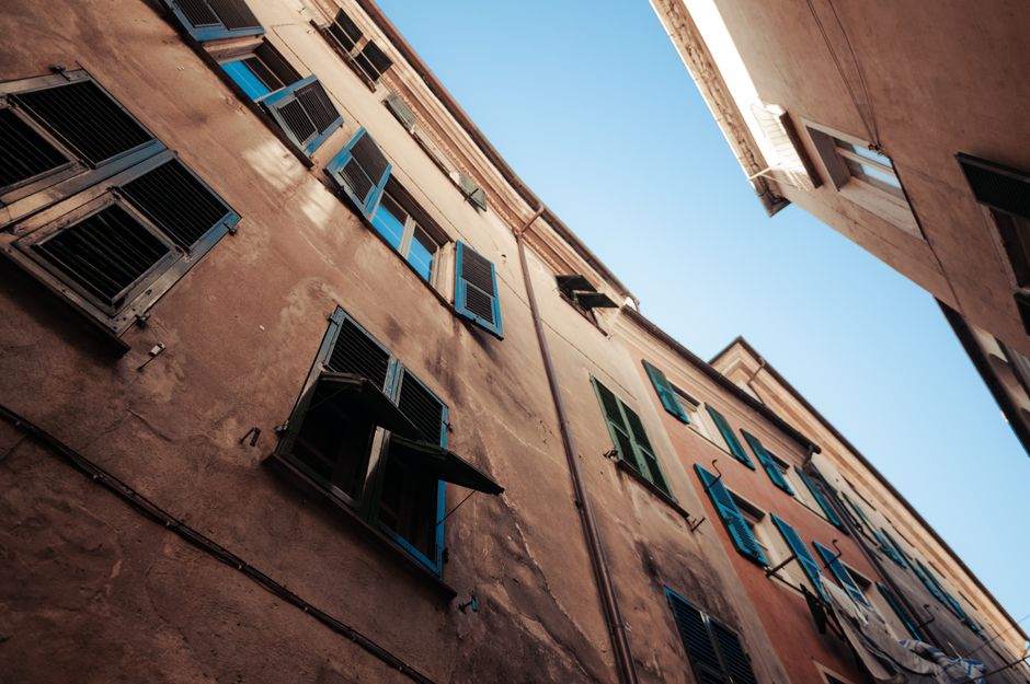 Low-angle view of vintage buildings with colorful window shutters against a clear blue sky.
