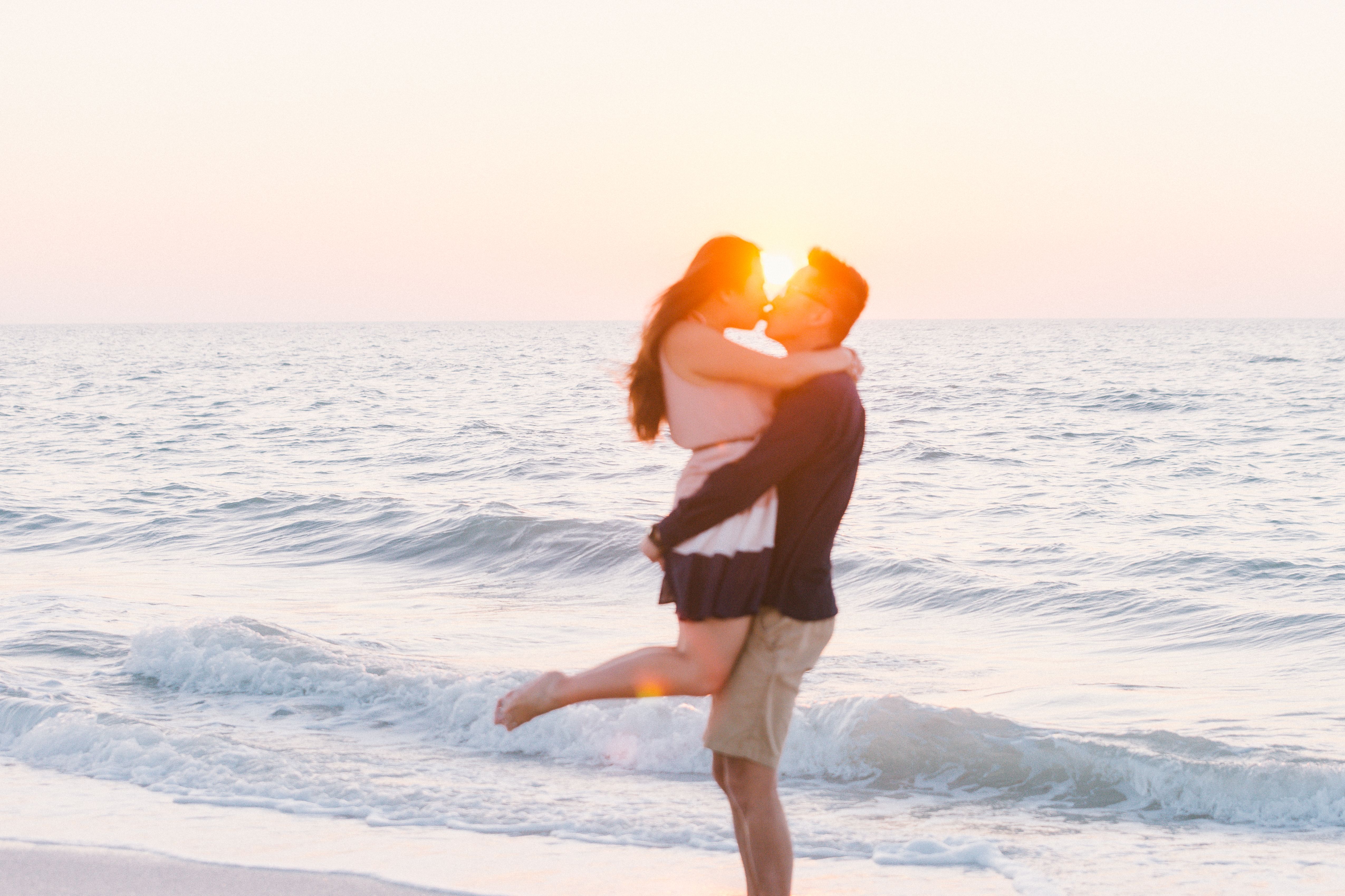 A couple shares a romantic kiss on the beach at sunset in Clearwater, Florida, capturing a moment of love and intimacy.