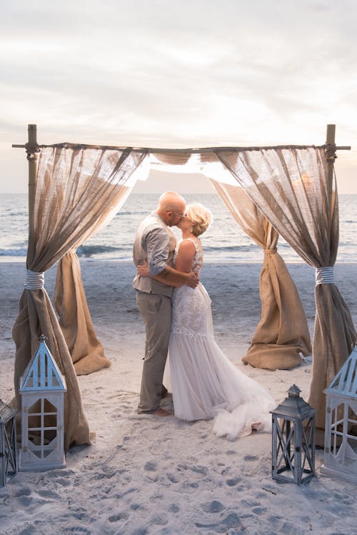 Photograph of a Couple Kissing on a Beach During their Wedding