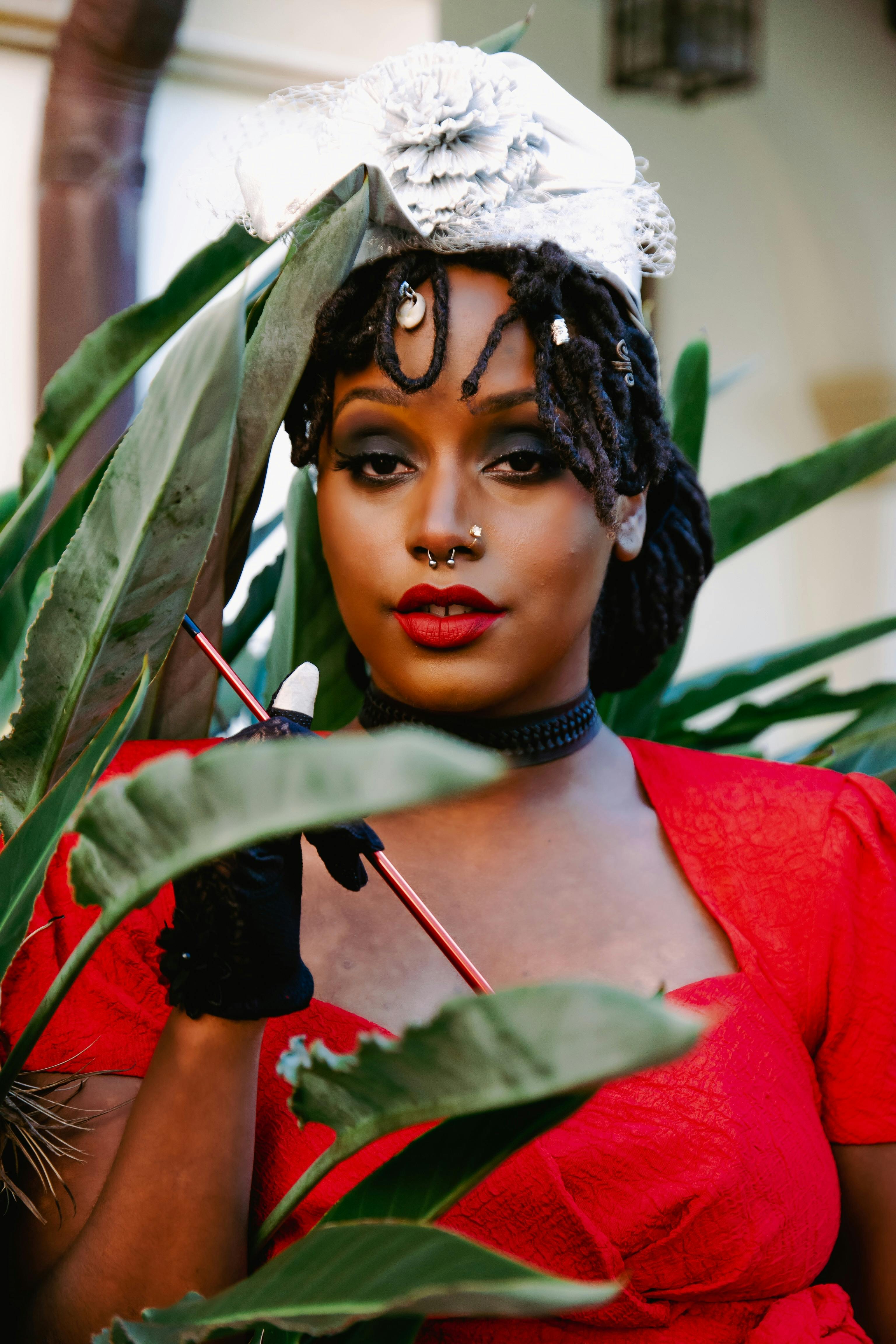 Portrait of a Woman in a Red Top Near Green Leaves · Free Stock Photo