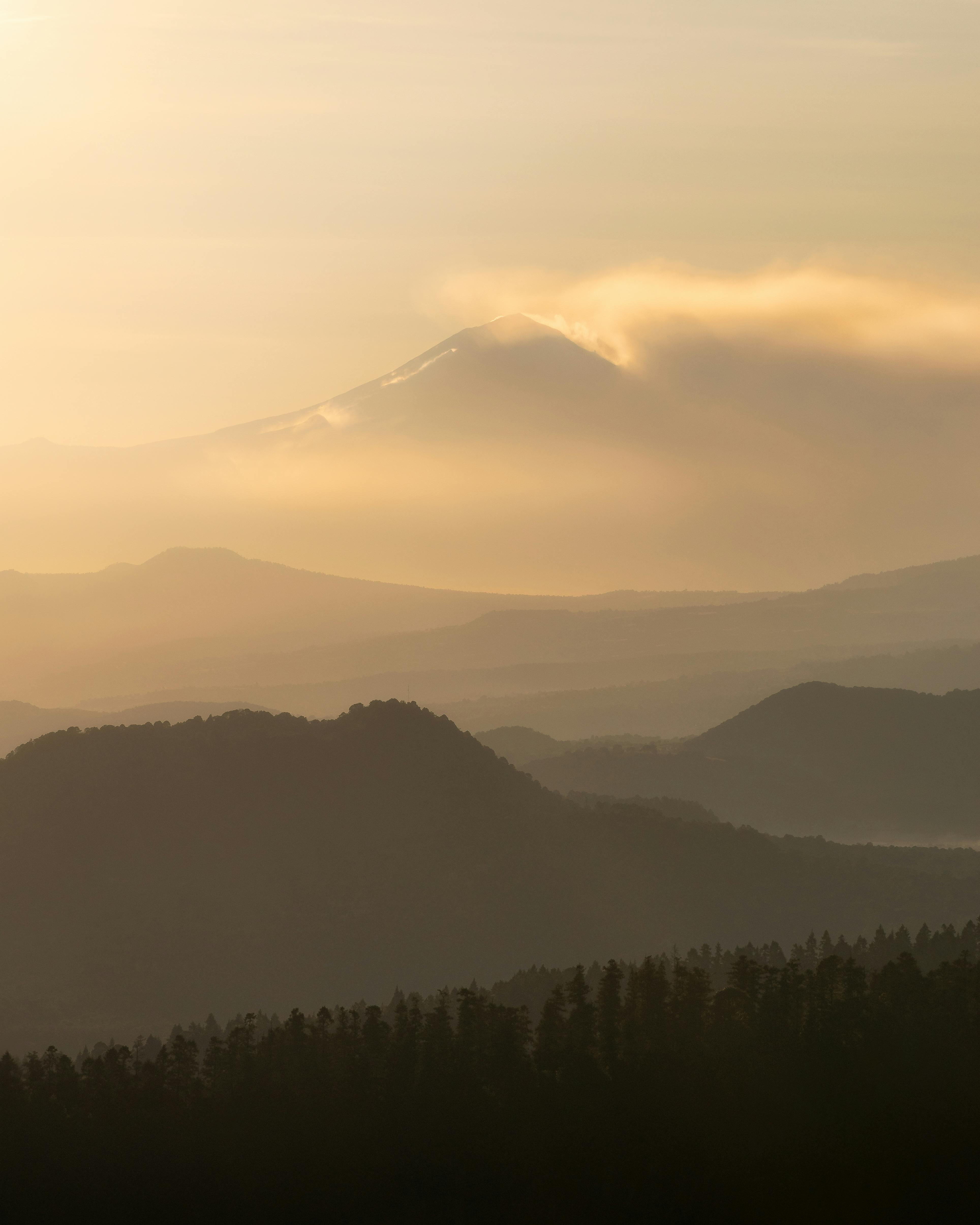Breathtaking sunrise over misty mountains near Mexico City, with clouds enhancing the serene landscape.