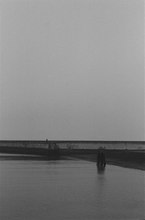 Free Serene monochrome seascape featuring a bridge under a vast sky. Stock Photo