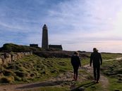 A Man and a Woman Standing on Green Grass Field Near Lighthouse