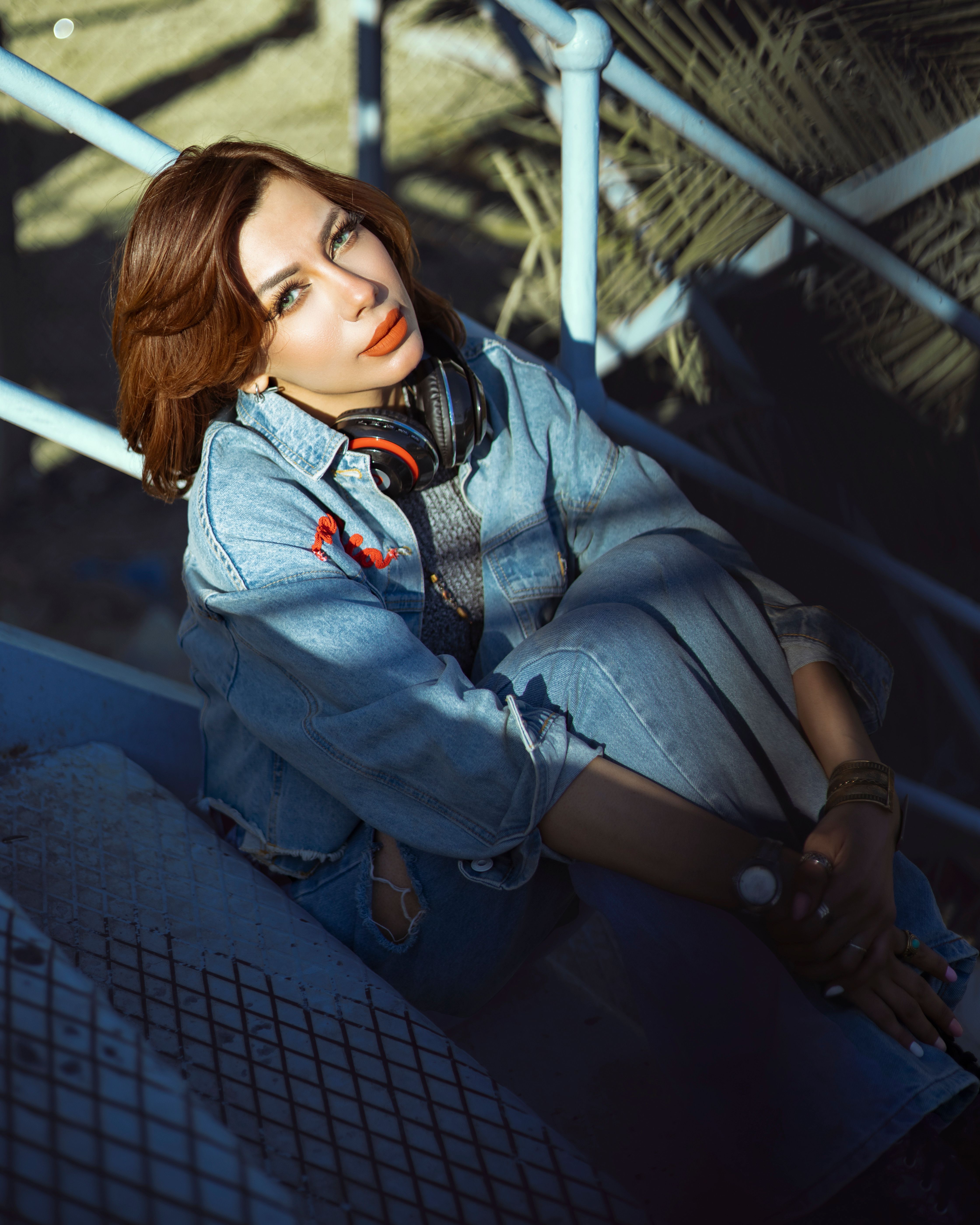 A Woman in Blue Denim Jacket and Blue Denim Jeans Sitting on Metal ...