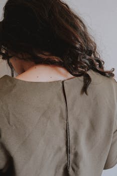 一位卷发女人穿着橄榄色连衣裙的艺术背影