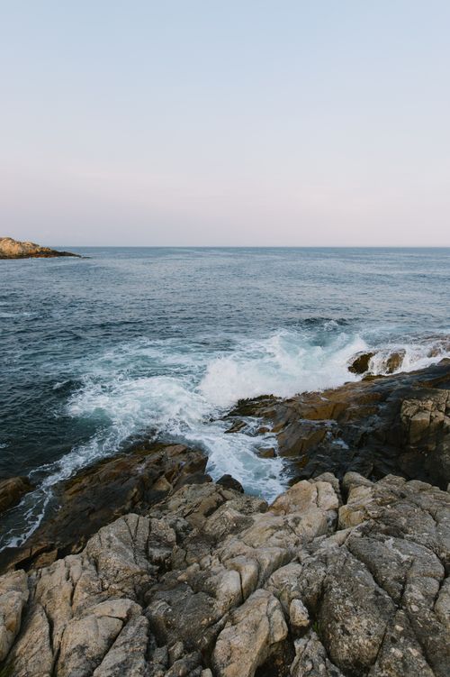 Free Serene view of waves crashing on rocky shore under a calm sky, perfect for nature enthusiasts. Stock Photo