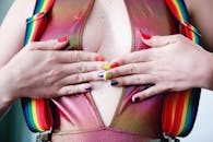 女性双手特写，彩虹指甲和背带展现出充满活力的风格