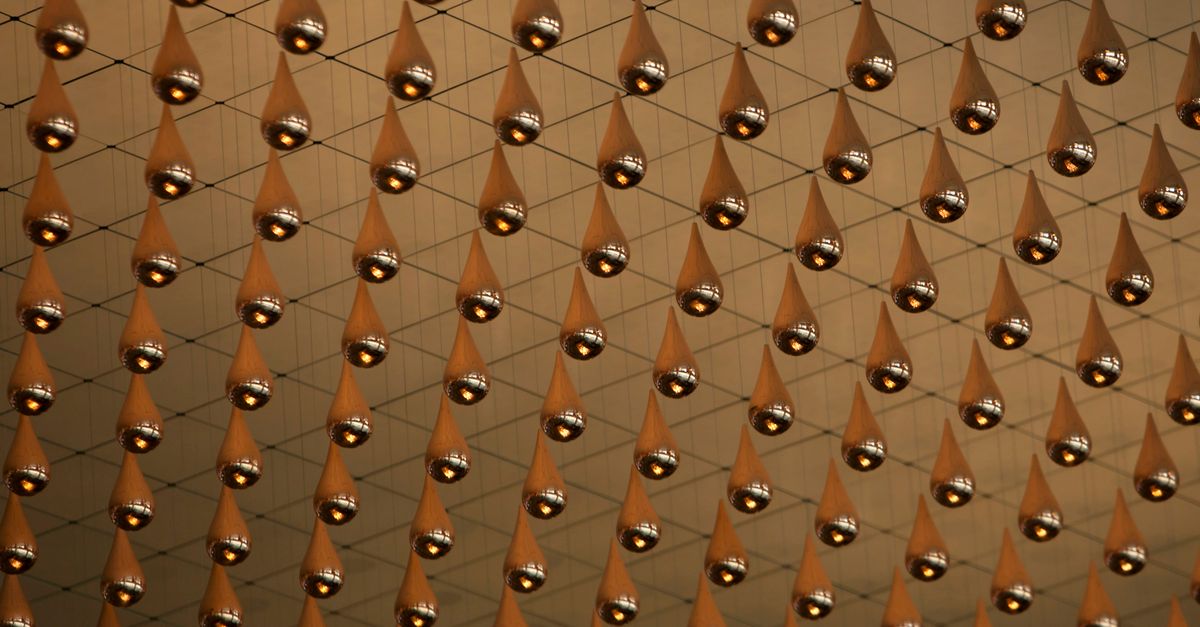 Metallic droplets suspended in an intricate net pattern, creating an immersive art installation.