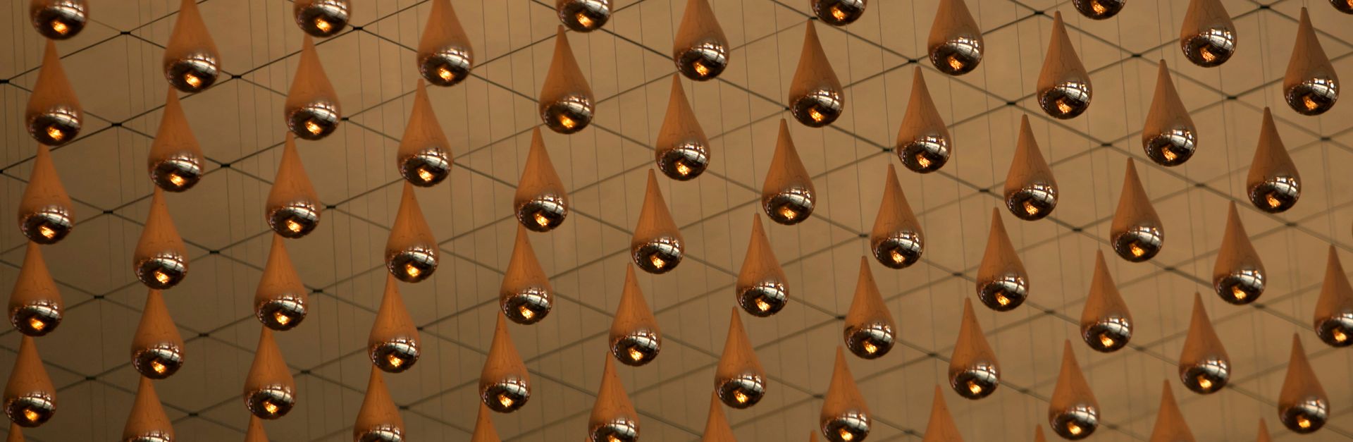 Metallic droplets suspended in an intricate net pattern, creating an immersive art installation.