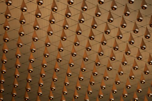 Free Metallic droplets suspended in an intricate net pattern, creating an immersive art installation. Stock Photo