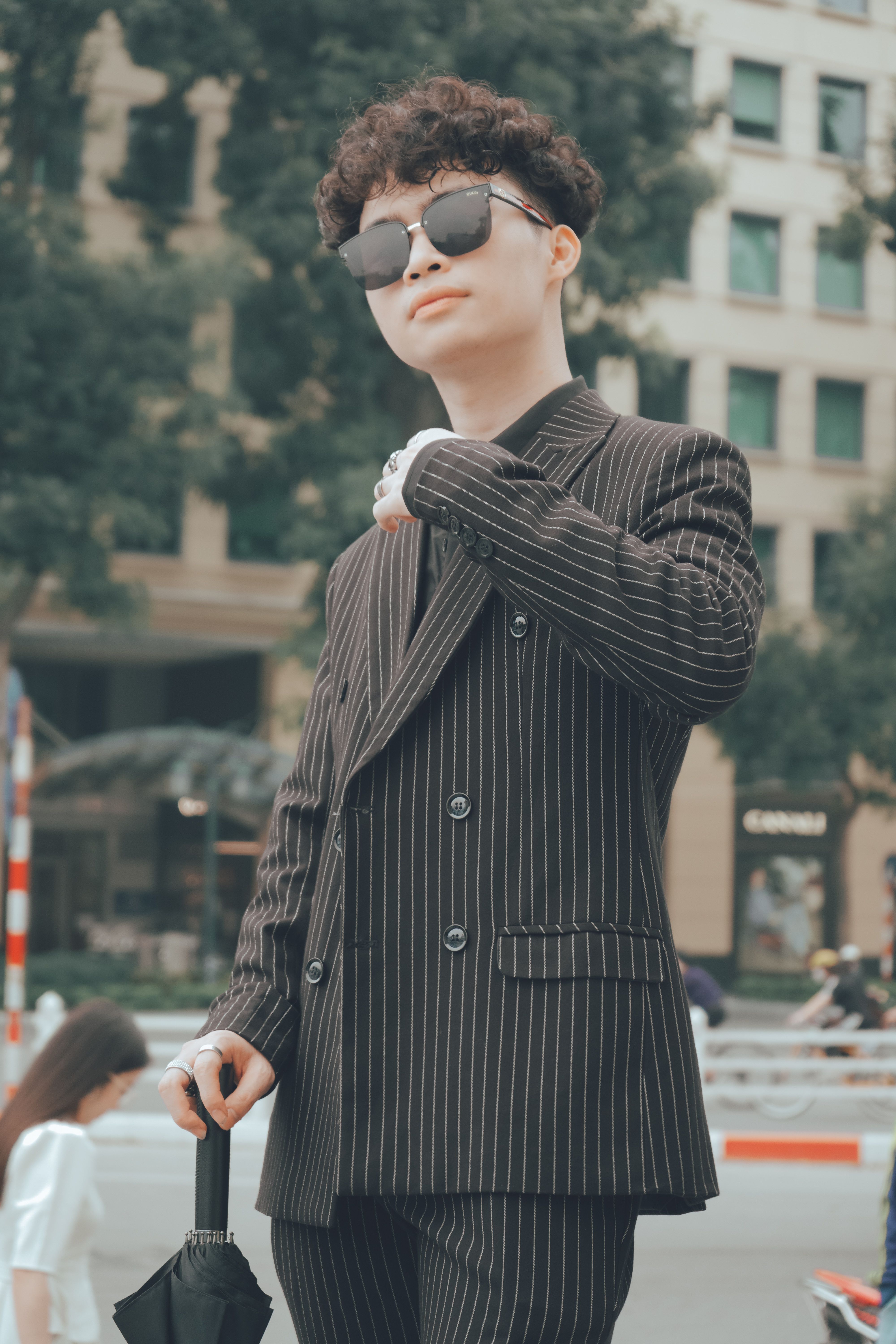 Modern Asian man in sunglasses striking a pose in Vietnam's urban setting.