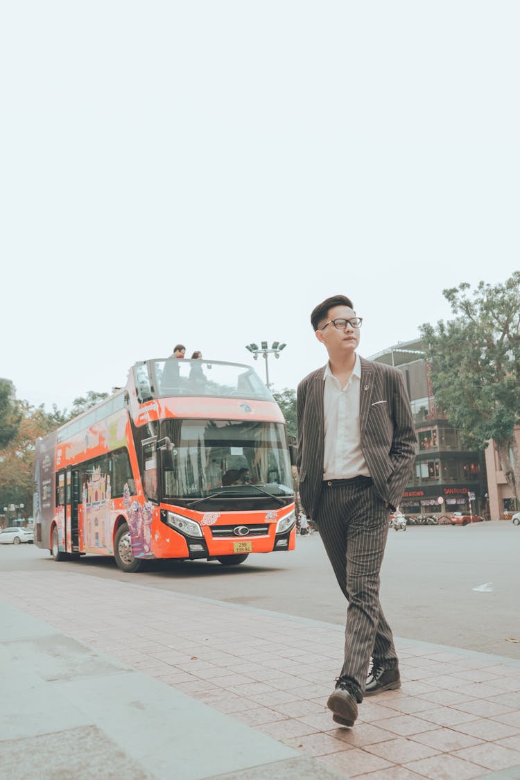 Photo Of A Walking Man With A Bus In The Background 