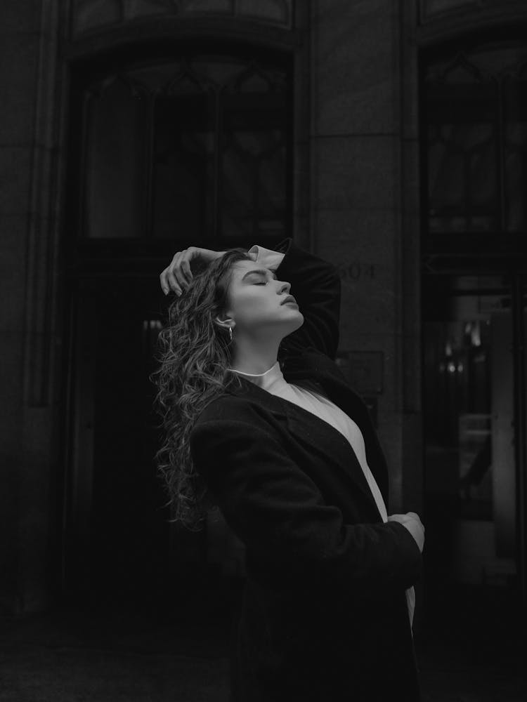 Young Woman In Jacket Posing With Hand Raised Above Head