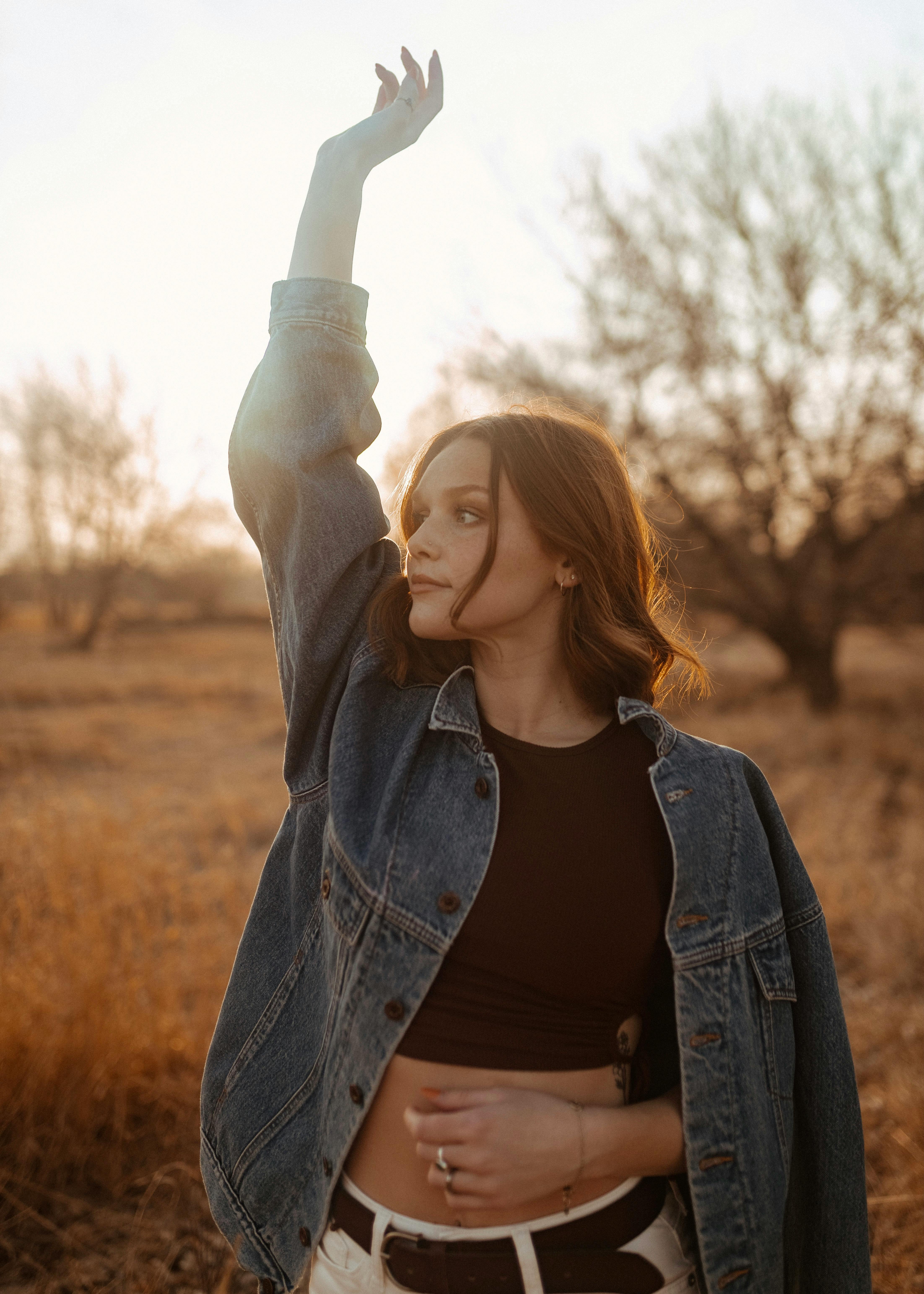 girl in denim jacket back lit by sun in fields