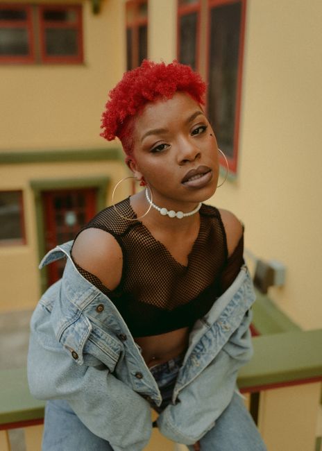 Fashionable portrait of a woman with red hairstyle and denim jacket in an outdoor setting in Des Moines.