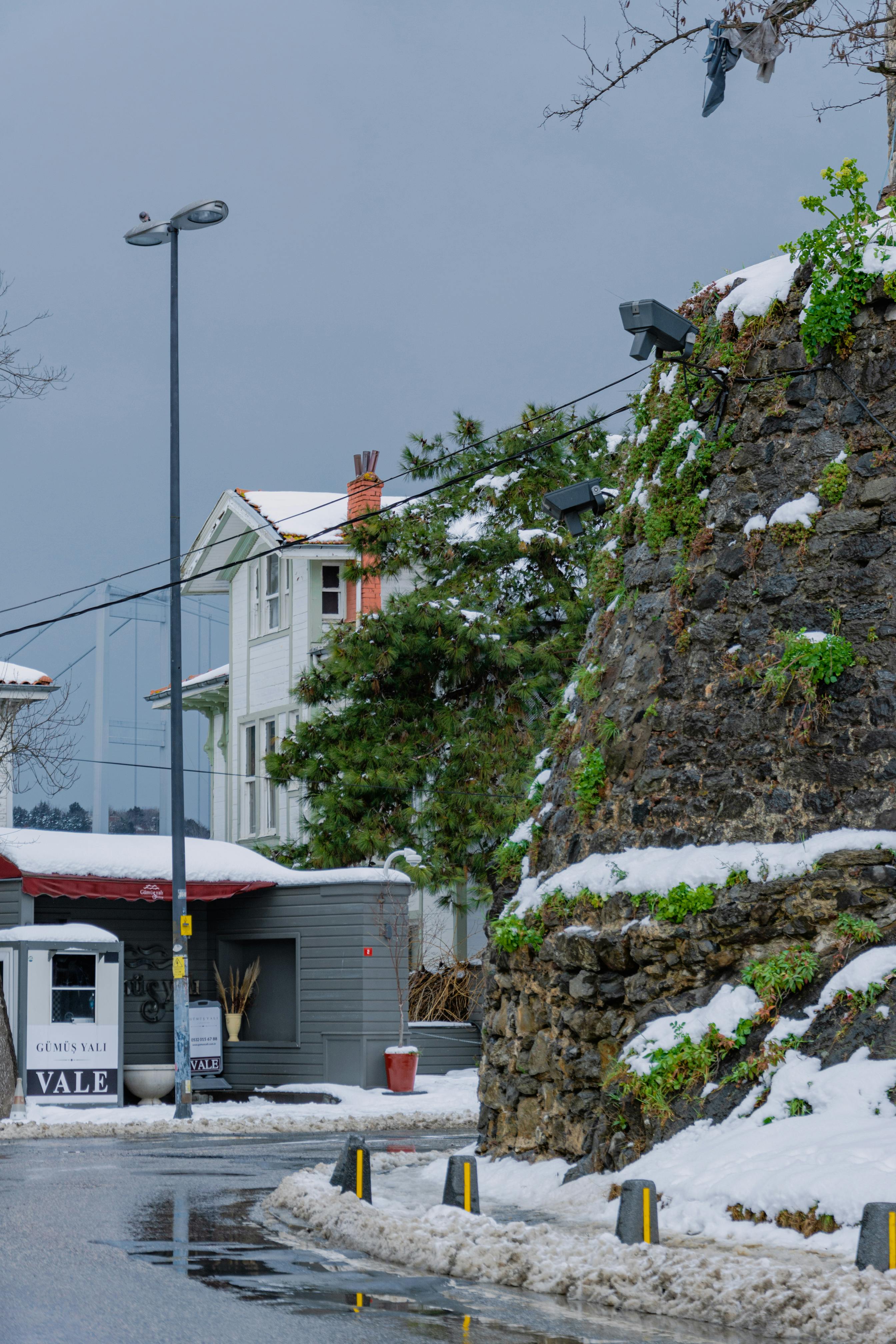 Free Winter scene of a snow-covered urban street next to a historic stone wall. Stock Photo