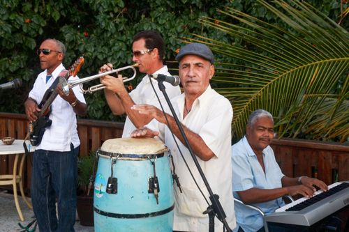Free Group of musicians performing outdoors, featuring guitar, trumpet, conga, and keyboard, showcasing live music and teamwork. Stock Photo