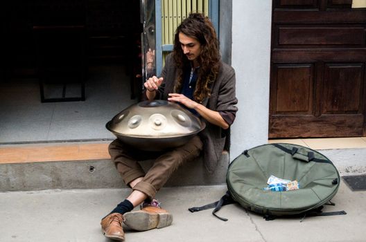 A man playing a hang drum on the sidewalk in Hanoi, Vietnam, creating soothing music.