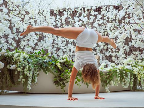Woman performing a handstand surrounded by vibrant flowers, showcasing fitness and grace.