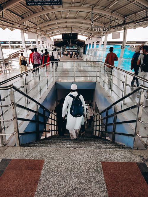 Free Commuters walking down stairs at a bustling railway station, showcasing travel and movement. Stock Photo