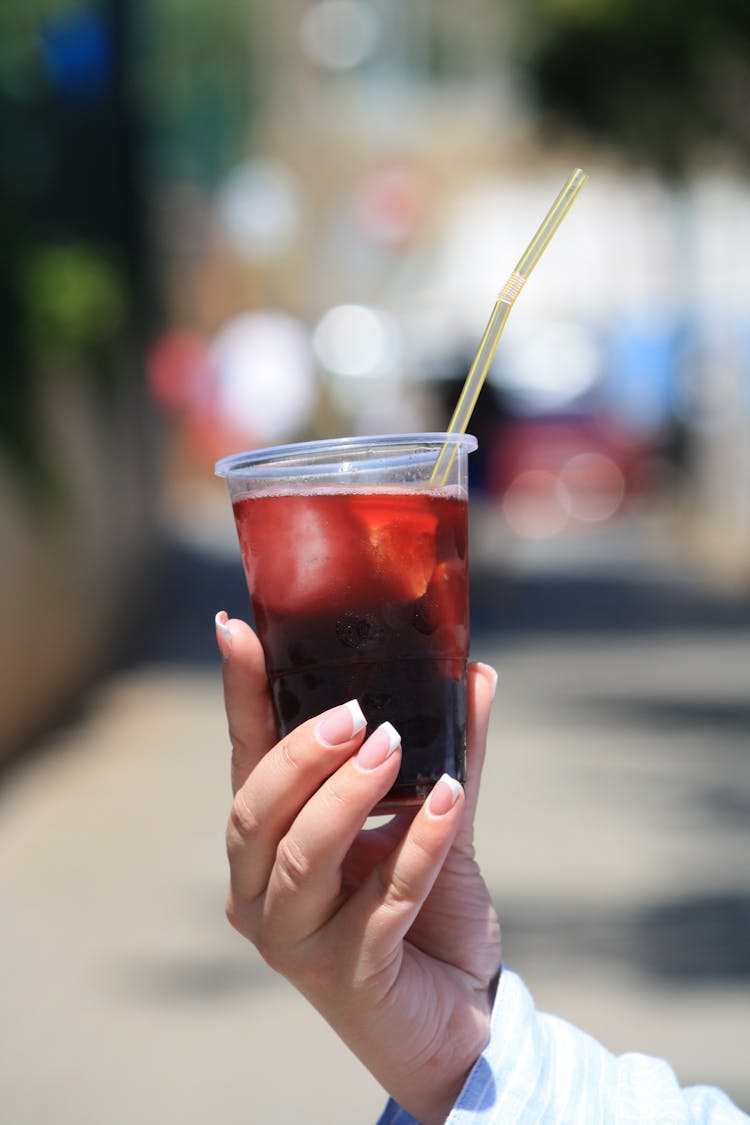 A Person Holding A Cup Of Refreshment