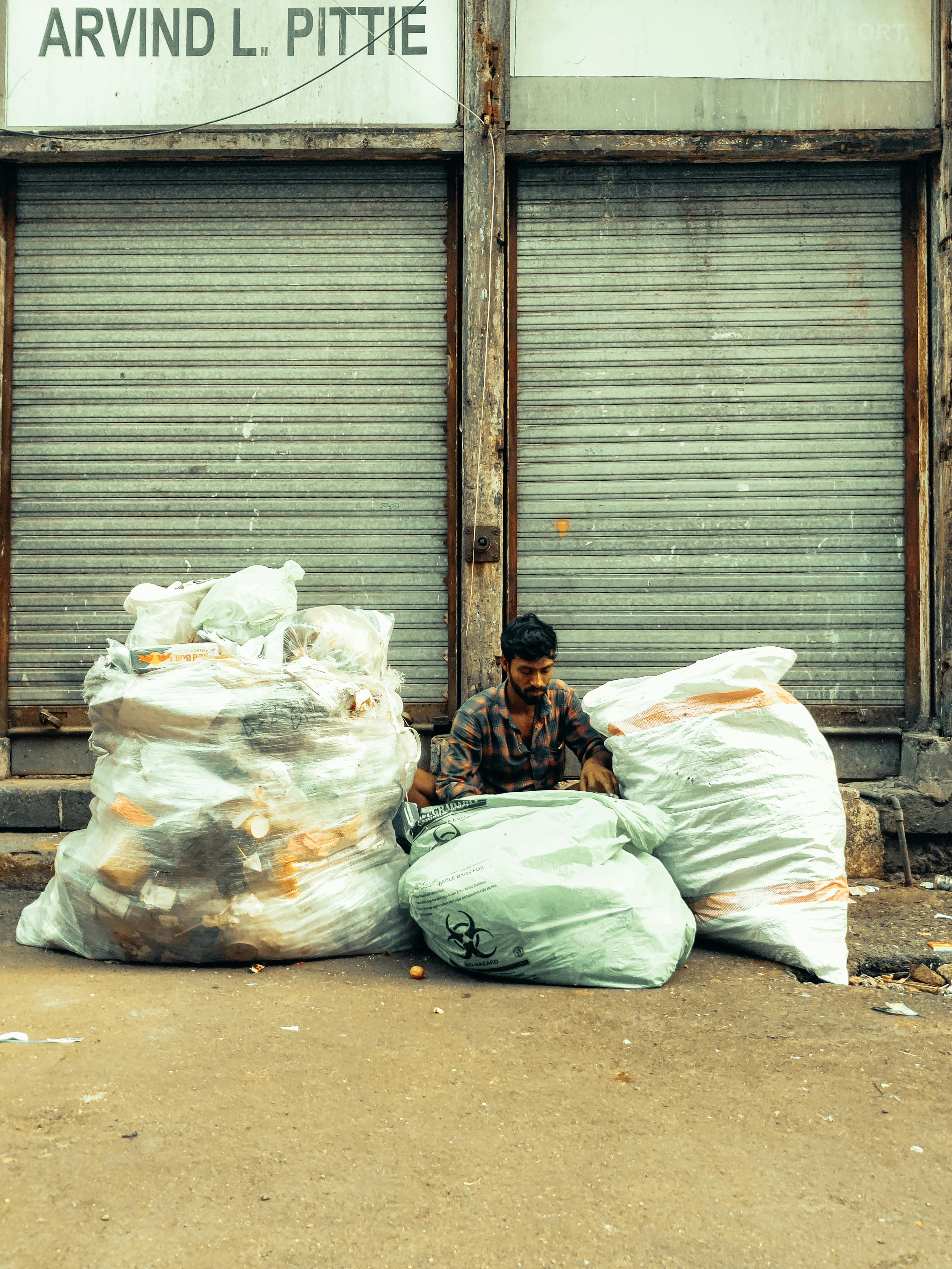 man sitting among bags of trash