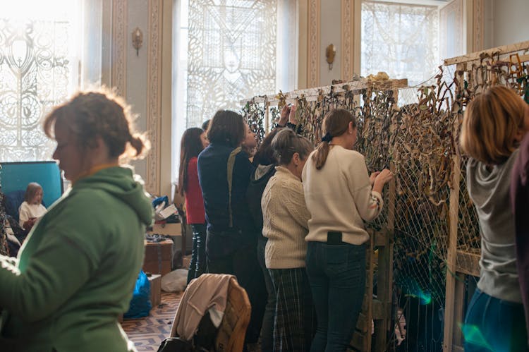 Group Of Women And Girls Weaving Masking Webs For Army