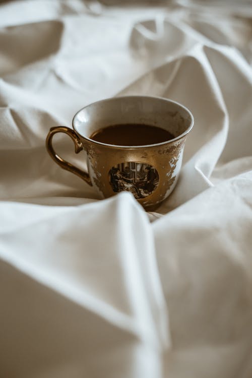 Porcelain Cup of Tea Lying on White Sheet