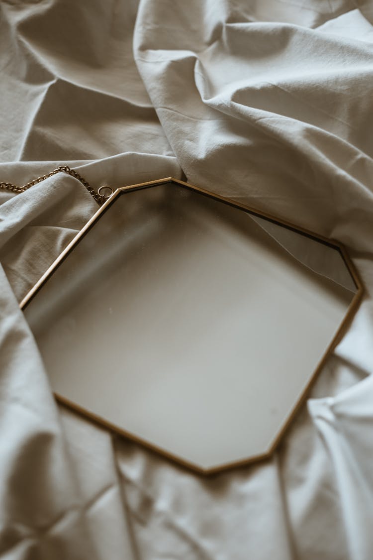 Square Mirror Lying On White Sheet