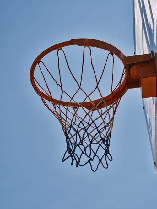 Free A close-up view of a basketball hoop against a clear blue sky, perfect for sports themes. Stock Photo